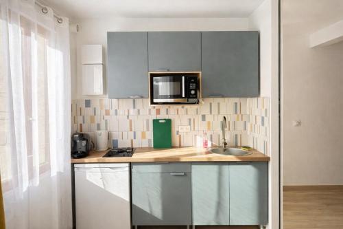 a kitchen with a sink and a microwave at Studio - Lit double - Proche Centrex & Disneyland in Noisy-le-Grand