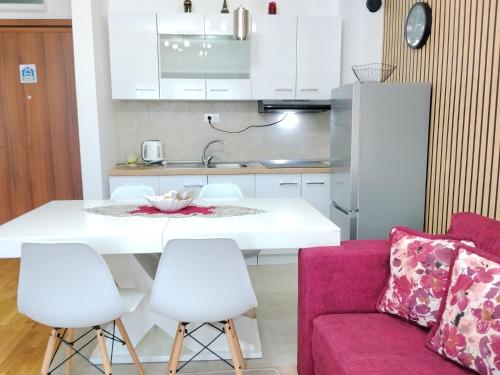 een keuken en woonkamer met een witte tafel en stoelen bij GREEN HILL Lux Apartments in Soko Banja