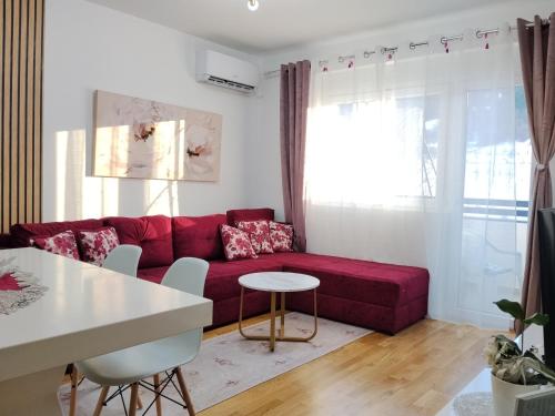 een woonkamer met een rode bank en een tafel bij GREEN HILL Lux Apartments in Soko Banja