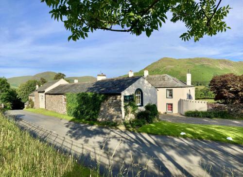 a house on a road with mountains in the background at Scale Hill Hotel in Loweswater