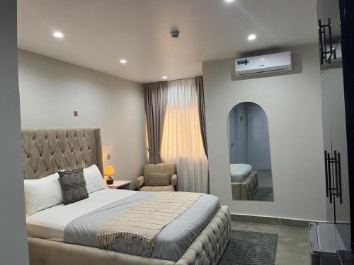 a bedroom with a bed and a chair and a mirror at Sylz Residence Studio in Accra