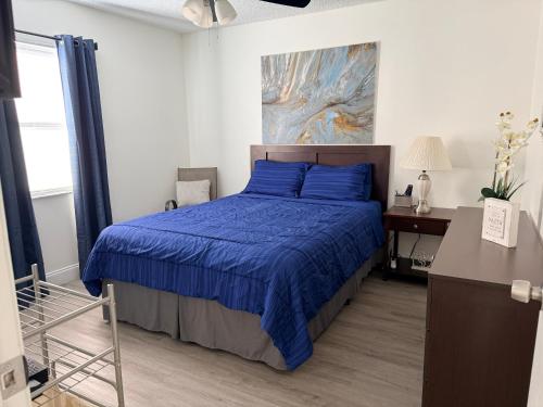 een slaapkamer met een blauw bed en een bureau bij Dos alcobas, entrada independiente in Kissimmee