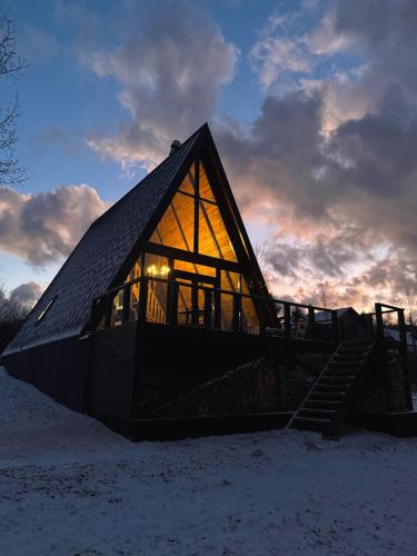 a small house with a glass facade in the snow at Lakewood Cabin - Surduc Lake in Fîrdea