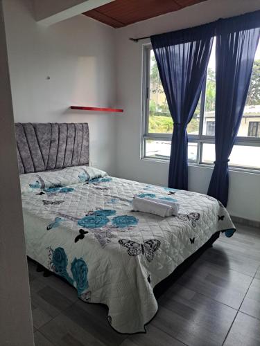 a bedroom with a large bed with blue curtains at Apartamento en La Colina in Macanal