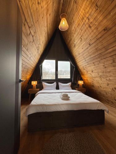 a bedroom with a large bed with a wooden ceiling at Lakewood Cabin - Surduc Lake in Fîrdea