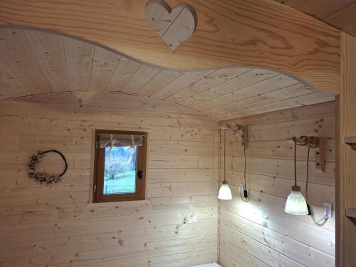 een kamer met een houten plafond met 2 verlichting en een raam bij Roulotte & Respire in Foussemagne