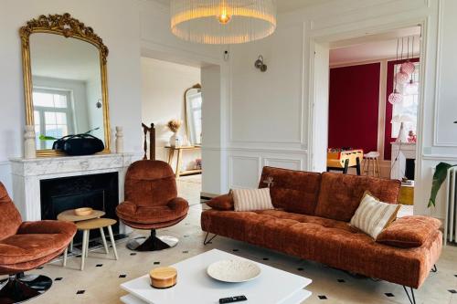 een woonkamer met een bank, stoelen en een spiegel bij Hôtel Particulier - 5 minutes de Reims in Reims