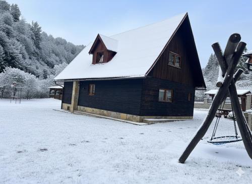 a barn with a snow covered roof and skis in the snow at Chata Sipkova I in Terchová