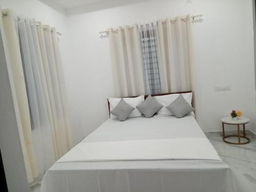 a bed with white sheets and pillows in a room at EVA Residency in Kallar