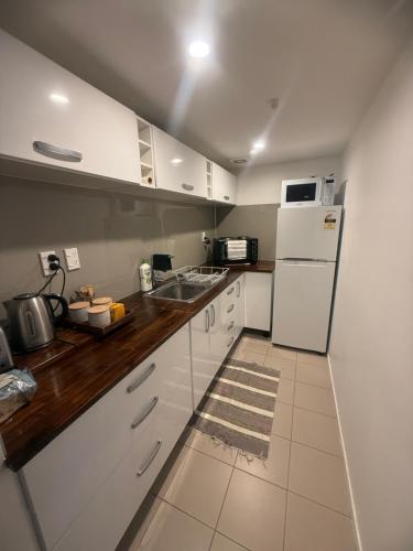 a kitchen with white cabinets and a white refrigerator at The Studio in Whangarei