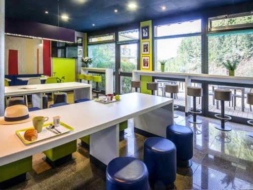 a restaurant with tables and stools and windows at ibis budget Cannes Mougins in Mougins