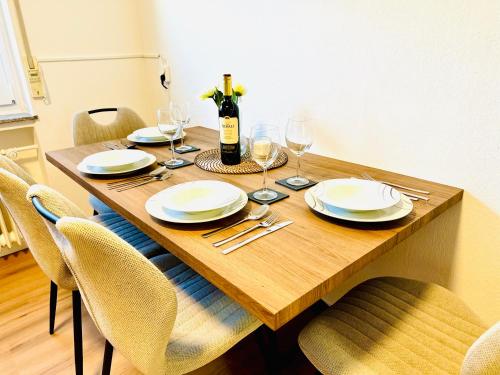 a wooden table with chairs and a bottle of wine at MOLA Apartments-Ruhrnahes Apartment mit Balkon & Parkplatz im Herzen von Schwerte-4P in Schwerte