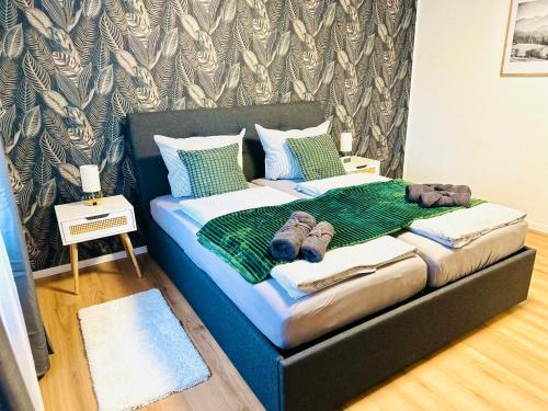 a bed with a green blanket and shoes on it at MOLA Apartments-Ruhrnahes Apartment mit Balkon & Parkplatz im Herzen von Schwerte-4P in Schwerte