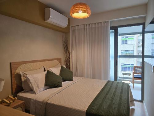 a bedroom with a bed and a window with a view at Conforto e Lazer a 50m da Praia in Niterói