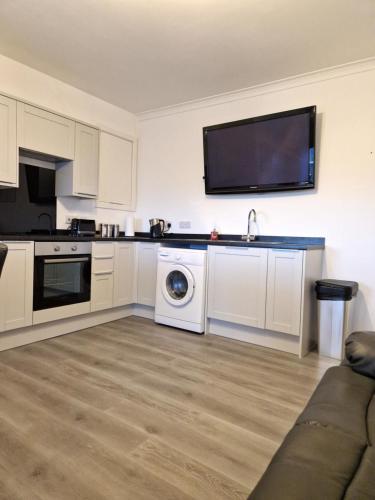 eine Küche mit einer Waschmaschine und einem TV an der Wand in der Unterkunft Rook View, Modern Coastal Retreat with Free Parking in Buckie