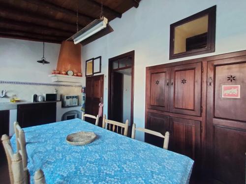 a dining room with a blue table and a kitchen at Casa Terra & Cal in Moura