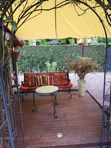 a patio with two benches and a table under an umbrella at La Garette in Elbeuf-sur-Andelle