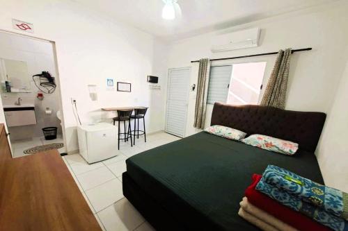 een slaapkamer met een bed en een keuken met een tafel bij Pousada Casa da Fernanda, Suíte Sun in Praia Grande