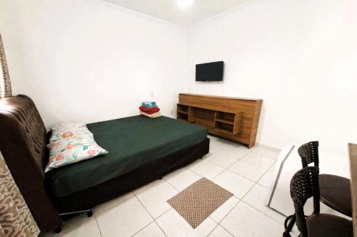 een slaapkamer met een bed, een tv en een stoel bij Pousada Casa da Fernanda, Suíte Sun in Praia Grande
