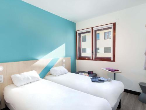 twee bedden in een kamer met een raam bij ibis budget Perpignan Centre Rénové en 2025 - Hôtel Economique au Centre ville de Perpignan in Perpignan