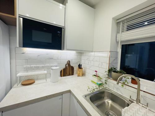 a white kitchen with a sink and a microwave at Modern, Brand-new Detached House in Oxford