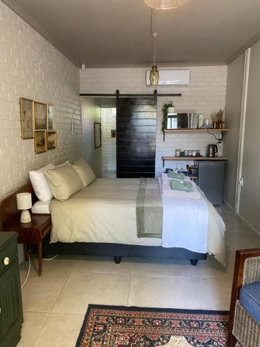 a bedroom with a large bed and a kitchen at The cozy acre in Potchefstroom