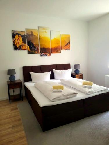 ein Schlafzimmer mit einem großen Bett mit vier Gemälden an der Wand in der Unterkunft Entspannen am Großen Goitzschesee in Holzweißig