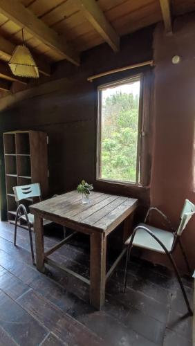 een houten tafel en stoelen in een kamer met een raam bij Raices del Mar in La Pedrera