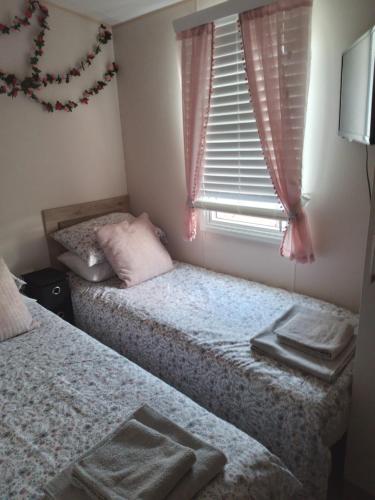 twee eenpersoonsbedden in een slaapkamer met een raam bij 2-bed Hide-away Caravan at Ashbourne Heights in Fenny Bentley