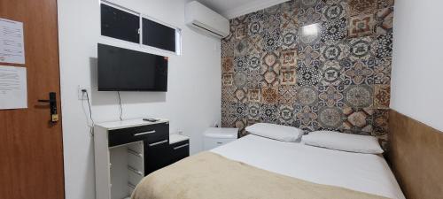 a small bedroom with a bed and a wall at Pousada Primeiro Sol in João Pessoa