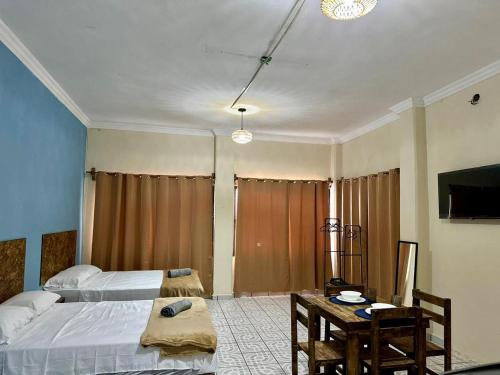 a bedroom with two beds and a table and a tv at Puerto 201 ROOMS in Veracruz