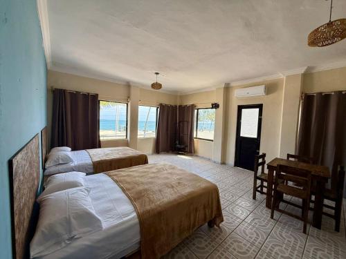 a bedroom with two beds and a desk and windows at Puerto 201 ROOMS in Veracruz