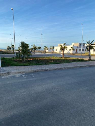 eine leere Straße mit Palmen am Straßenrand in der Unterkunft Mini villa trougout in Al Hoceïma