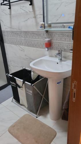 a bathroom with a sink and a trash can at Mini villa trougout in Al Hoceïma