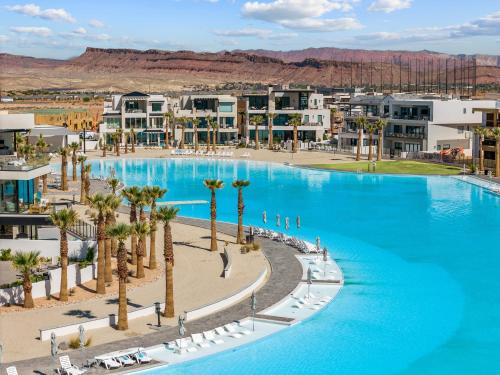 a large pool with palm trees and buildings at Weekend Vibes townhouse in St. George