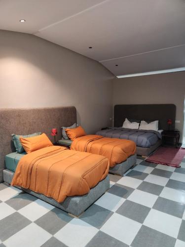 sypialnia z 2 łóżkami i podłogą wyłożoną szachownicą w obiekcie bourrous luxury camp w mieście Oulad Boudene