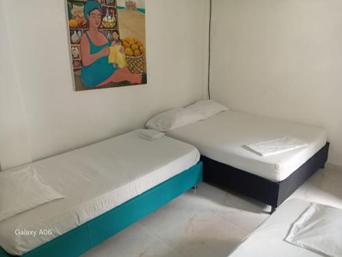 due letti in una stanza con un quadro sul muro di Hostal Paloma Café a Palomino