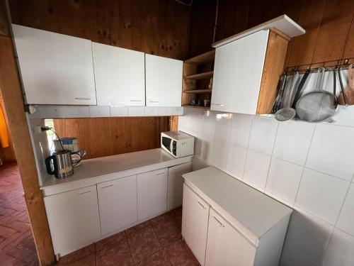 una cucina con mobili bianchi e un forno a microonde di Casa en el centro de Licanray a Licán Ray