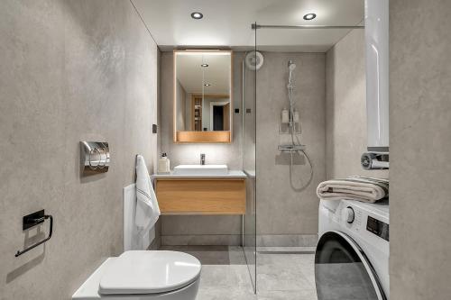 a bathroom with a toilet and a sink and a washing machine at Unique Tromsø mini-house! in Tromsø