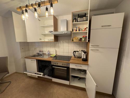 una cucina con mobili bianchi e una stufa di Apartment 3 ABG69 - ideal für Familien und Geschäftsreisende a Gera