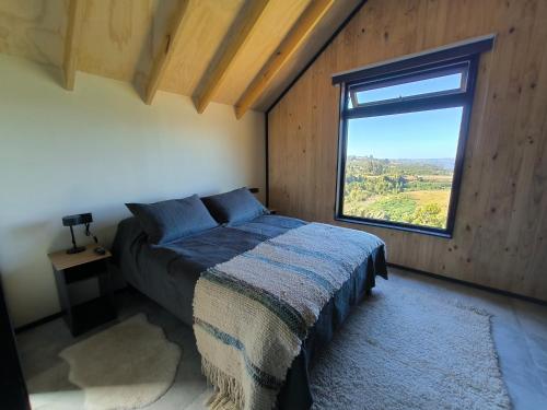 a bedroom with a bed and a large window at Casa Esquila de Chiloé in Chonchi