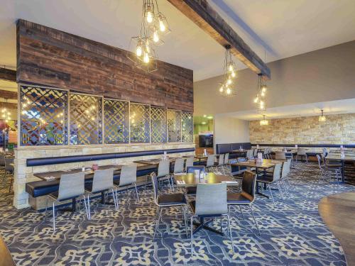 una sala da pranzo con tavoli, sedie e un muro di mattoni di Mercure Warragul a Warragul