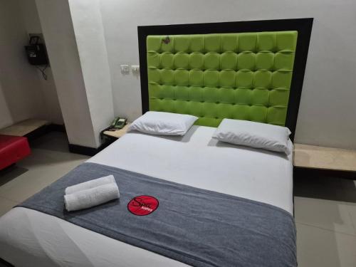 ein Schlafzimmer mit einem großen Bett mit grünem Kopfteil in der Unterkunft Hotel Spa Laureles in Medellín