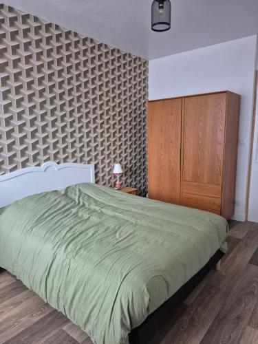 een slaapkamer met een groen bed en een houten kast bij Le break en nord Cotentin in Cherbourg en Cotentin