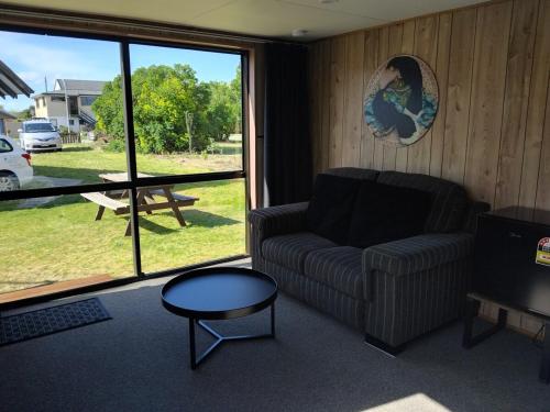 een woonkamer met een bank, een tafel en een raam bij TuiStay in Cromwell