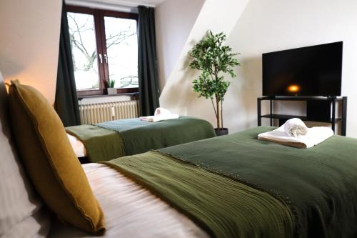 two green beds in a room with a tv at Nalia Homes - Elegant Central Apartment in Pinneberg