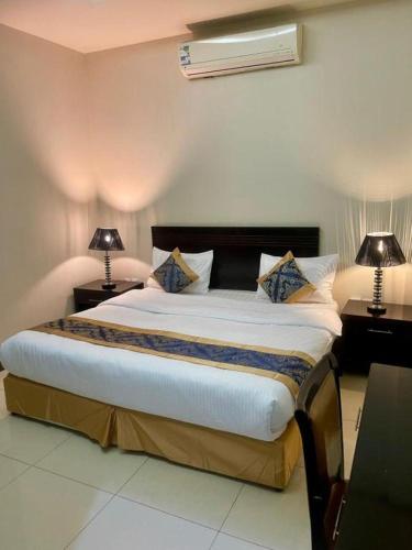 a bedroom with a large bed with two tables and two lamps at Quiet Rooms 8 Serviced Apartments in Riyadh