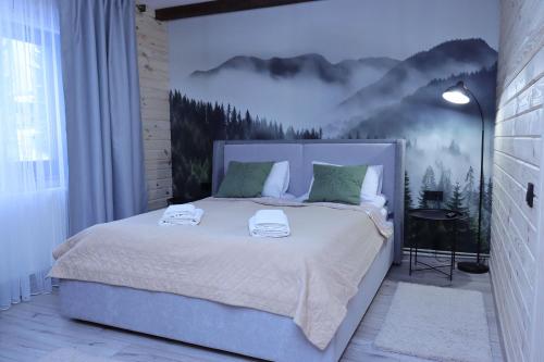 een slaapkamer met een groot bed met een schilderij aan de muur bij Садиба "Hutsulyana" in Dobrovelychkivka