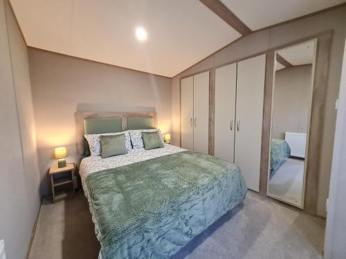 a bedroom with a large bed and a mirror at Silversands - Private Caravan Let in Lossiemouth