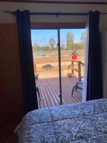 a bedroom with a bed and a view of a deck at Cabaña Palmas de Tunquen in Tunquén
